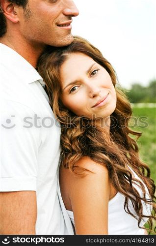 Young woman smiling at camera as she leans on her man