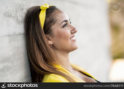 Young woman smiling wearing a yellow jacket and headband outdoors. Young woman wearing a yellow jacket and headband smiling.