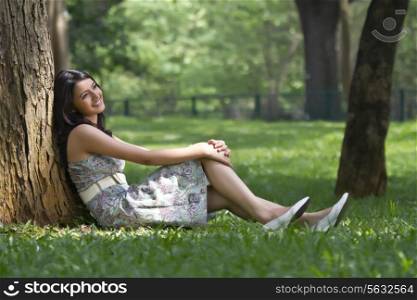 Young woman smiling while leaning against a tree