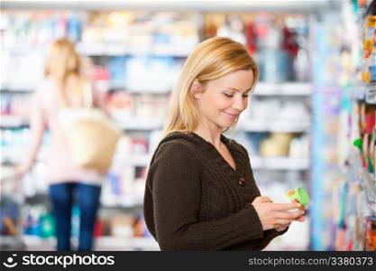 Young woman smiling while shopping in the supermarket with people in the background