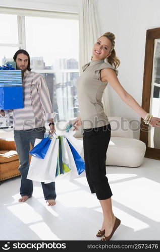 Young woman smiling with a young man holding shopping bags beside her