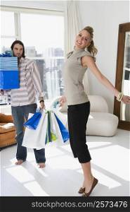 Young woman smiling with a young man holding shopping bags beside her