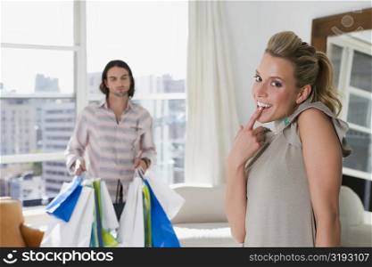 Young woman smiling with a young man holding shopping bags in the background