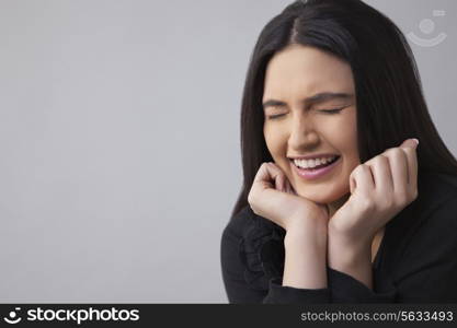 Young woman smiling with eyes closed over colored background