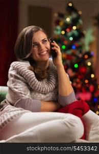 Young woman speaking mobile phone in front of Christmas tree