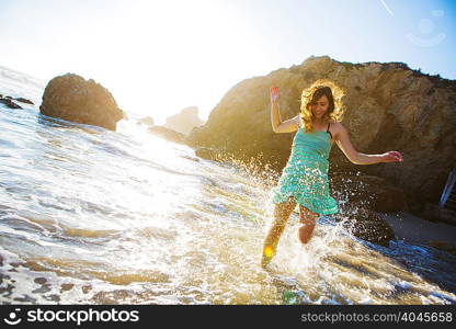 Young woman splashing in water on beach