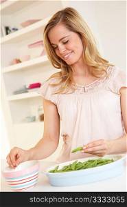 Young woman splitting pea in kitchen