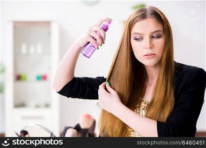 Young woman spraying hair polish to her hair
