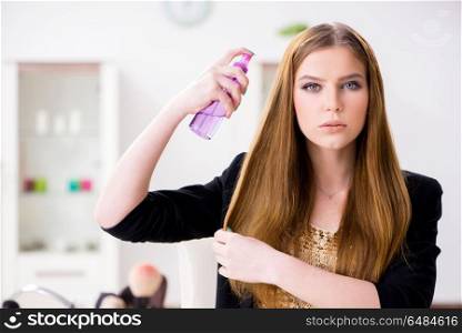 Young woman spraying hair polish to her hair