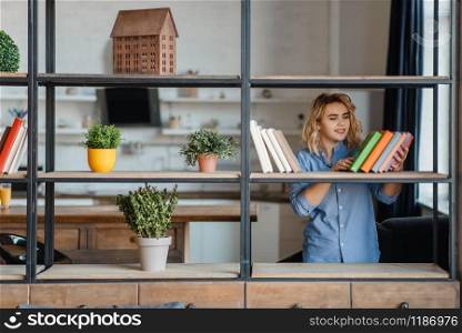 Young woman sprays home plants on the shelf in living room, florist hobby. Female person takes care of domestic flowers, flora growing, gardening. Young woman sprays home plants on the shelf