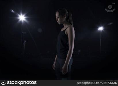Young woman standing against lights in dark