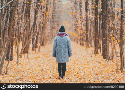 Young woman standing alone along trail in autumn forest. Back view. Travel, freedom, nature concept. Young woman standing alone along trail in autumn forest. Back view. Travel, freedom, nature concept.