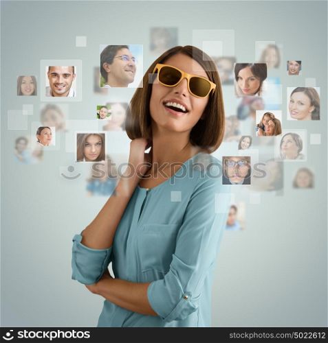 Young woman standing and smiling with many different people's faces around her. Technology social media network of friends and communication.