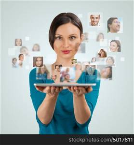 Young woman standing and smiling with many different people's faces flying from her tablet computer. Technology social media network concept