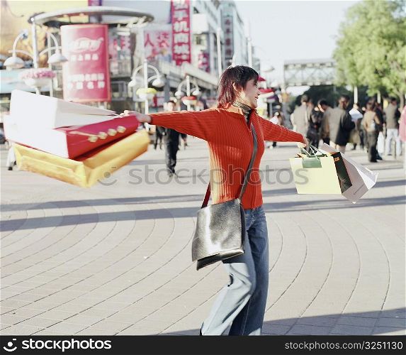 Young woman standing and swinging shopping bags