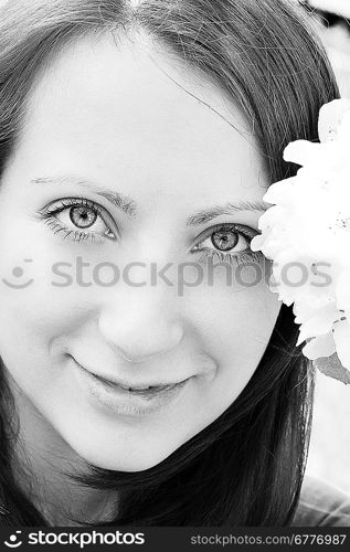 Young woman standing at apple tree in white blossom