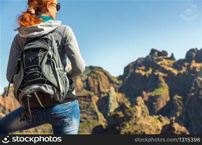 Young woman standing back with a backpack in mountains. Young girl in mountains