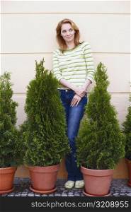 Young woman standing behind potted plants