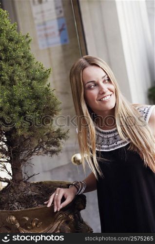 Young woman standing beside a potted plant