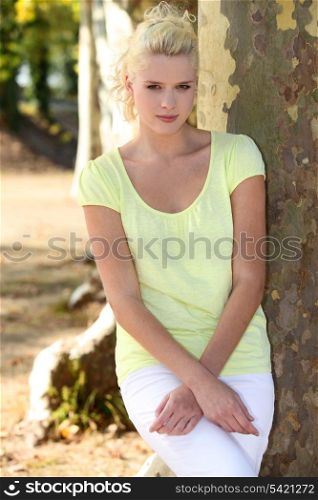 Young woman standing by a plane tree