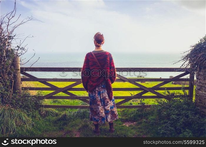 Young woman standing by fence