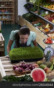 Young woman standing in a grocery store and looking at wheatgrass