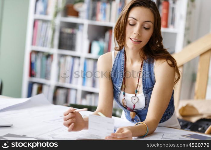 Young woman standing in creative office. Smiling young designer standing in creative office in front of her desk