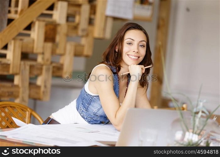 Young woman standing in creative office. Smiling young designer standing in creative office in front of her desk