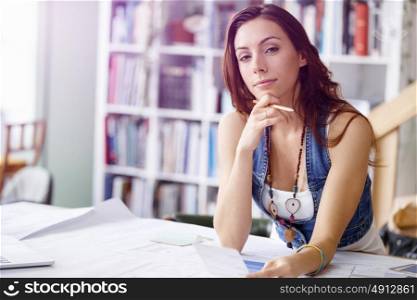 Young woman standing in creative office. Smiling young designer standing in creative office in front of her desk