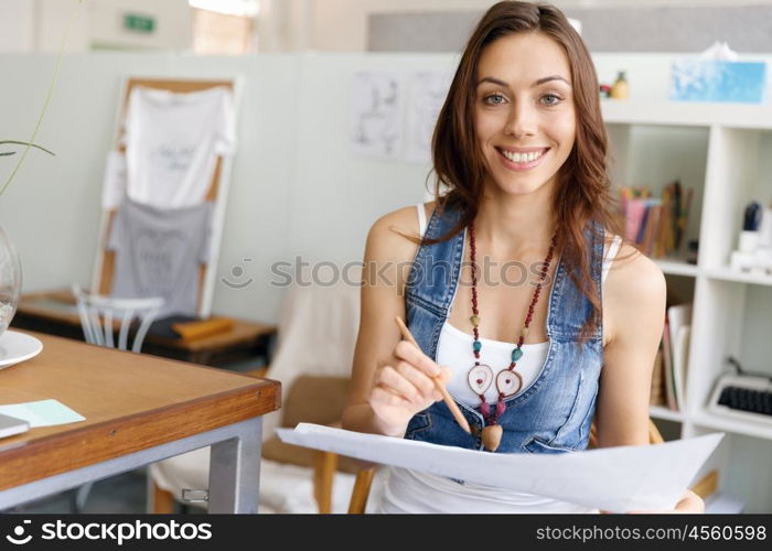 Young woman standing in creative office. Smiling young designer standing in creative office