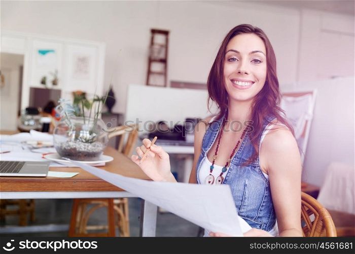 Young woman standing in creative office. Smiling young designer standing in creative office