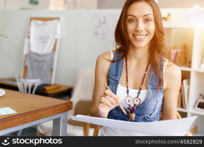 Young woman standing in creative office. Smiling young designer standing in creative office