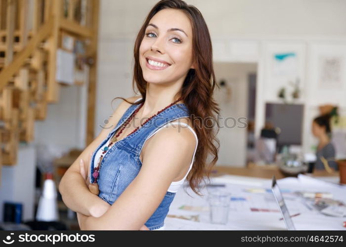 Young woman standing in creative office. Smiling young designer standing in creative office