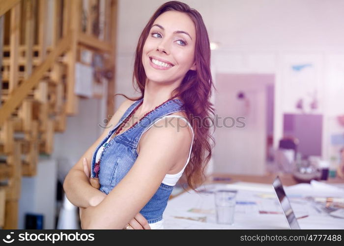 Young woman standing in creative office. Smiling young designer standing in creative office