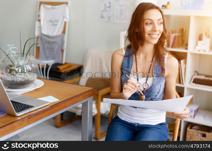 Young woman standing in creative office. Smiling young designer standing in creative office