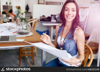 Young woman standing in creative office. Smiling young designer standing in creative office