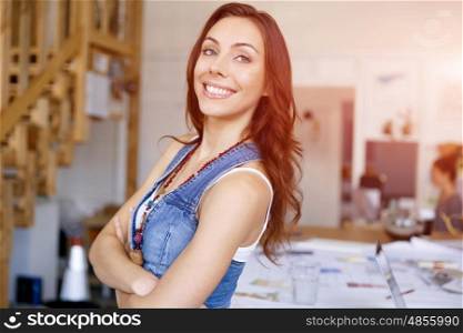 Young woman standing in creative office. Smiling young designer standing in creative office