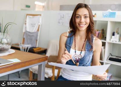 Young woman standing in creative office. Smiling young designer standing in creative office