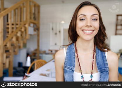 Young woman standing in creative office. Smiling young designer standing in creative office