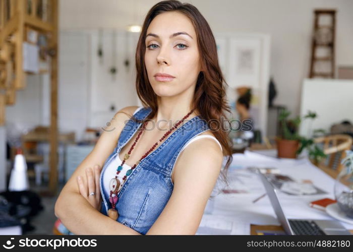 Young woman standing in creative office. Smiling young designer standing in creative office