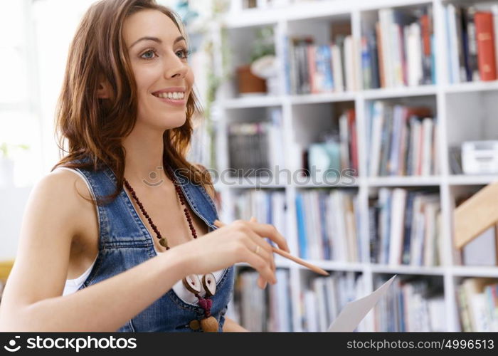 Young woman standing in creative office. Smiling young designer standing in creative office