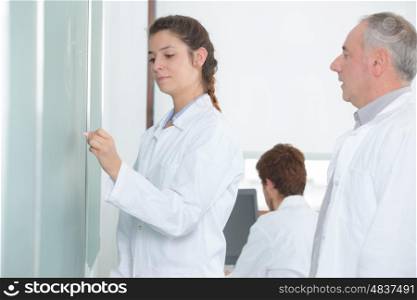 young woman standing in front of white board and teacher