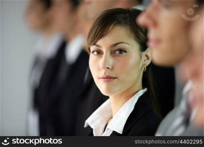 Young woman standing in line with co-workers