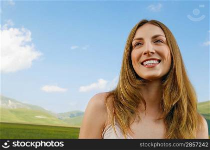Young woman standing in mountain field, close up, front view