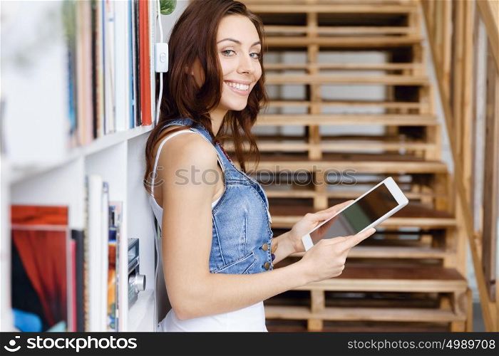 Young woman standing in office with notepad. Smiling young designer standing in office and holding notepad