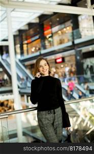 Young woman standing in shopping mall talking over mobile phone