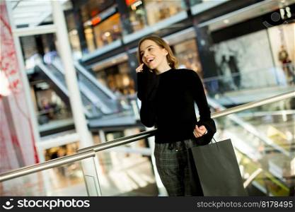 Young woman standing in shopping mall talking over mobile phone
