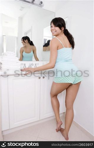 Young woman standing in the bathroom leaning against a bathroom sink