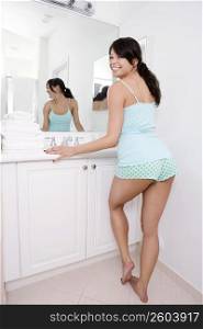 Young woman standing in the bathroom leaning against a bathroom sink