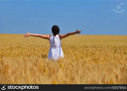 Young woman standing jumping and running on a wheat field with blue sky the background at summer day representing healthy life and agriculture concept